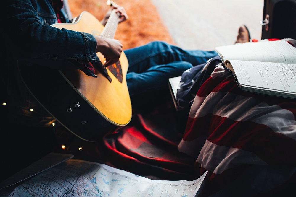 Person sitting playing an acoustic guitar