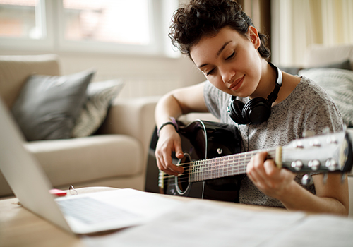 Girl playing piano at home in front of a laptop at home