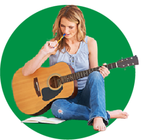 A woman sitting holding a guitar while making notes