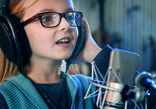 Girl singing into microphone wearing headphones