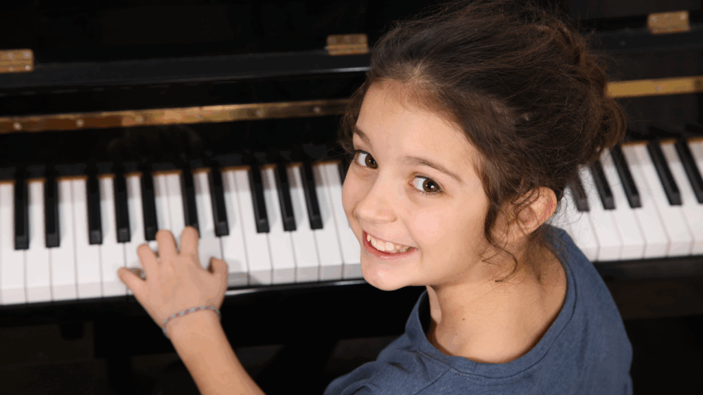 Young girl performing on stage at a piano recital, showcasing focus and confidence.