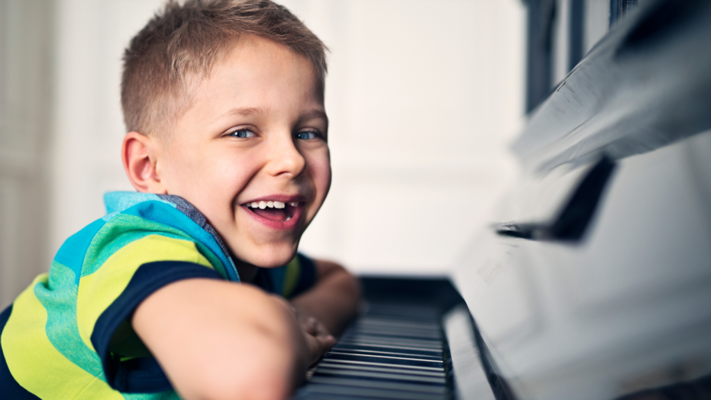 Confident child smiling at the piano, showing the social benefits of music lessons for kids.
